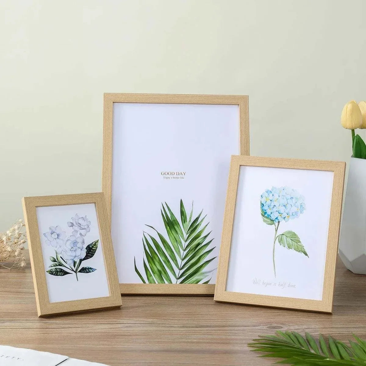 Wooden Photo Frame set featuring light natural wood with clean lines, holding botanical prints of green leaves and blue flowers
