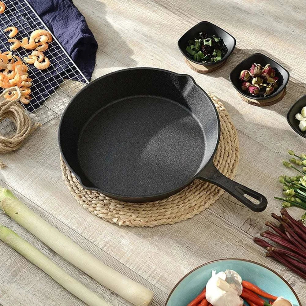 Cast Iron Cookware Set featuring a black uncoated cast iron frying pan with a handle, placed on a woven mat.