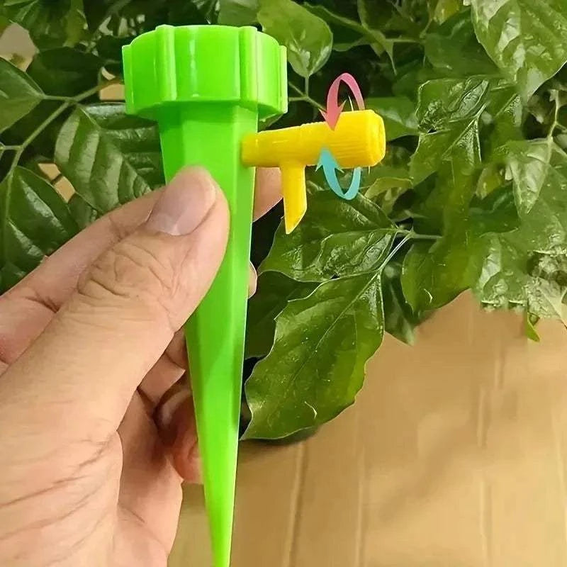 Flower Adjustable Drip Tool in green and yellow plastic held by hand with directional arrows on yellow nozzle for watering plants